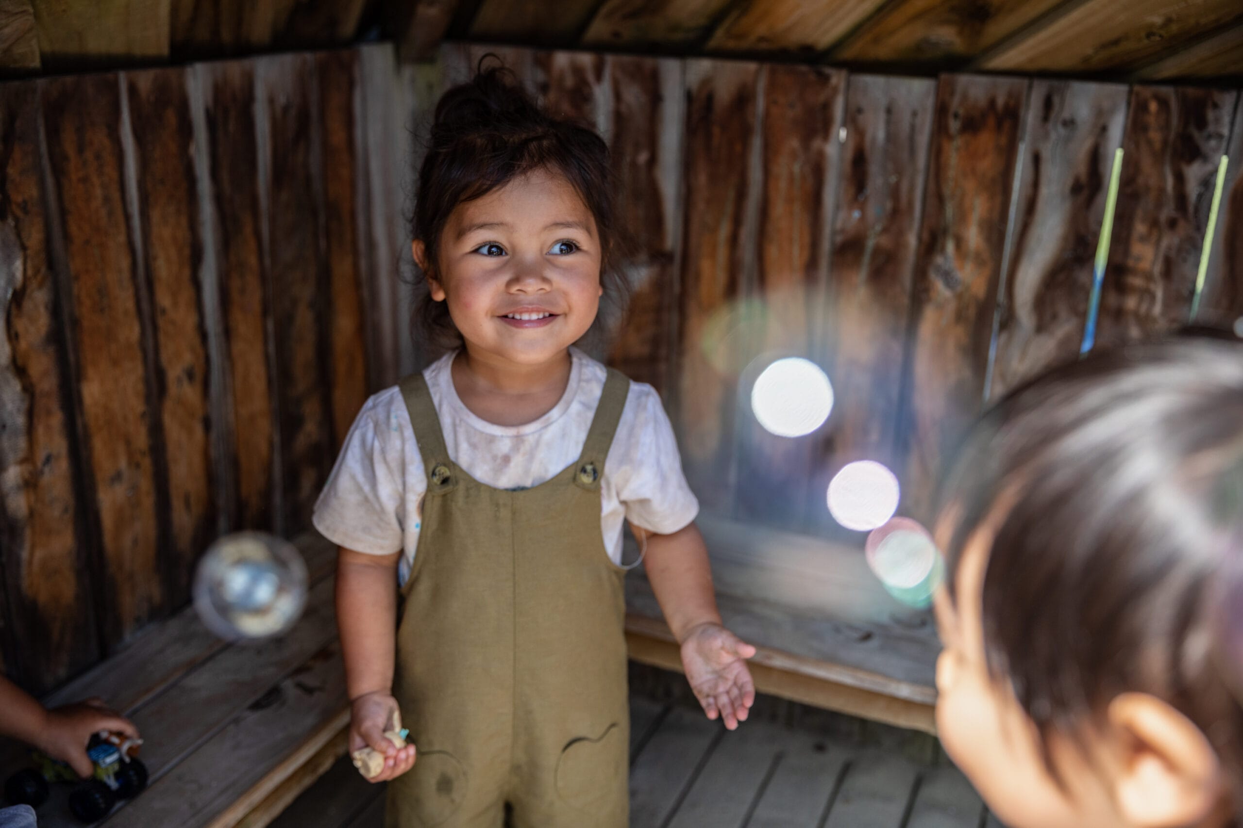 little girl smiling and playing with bubbles, book a visit